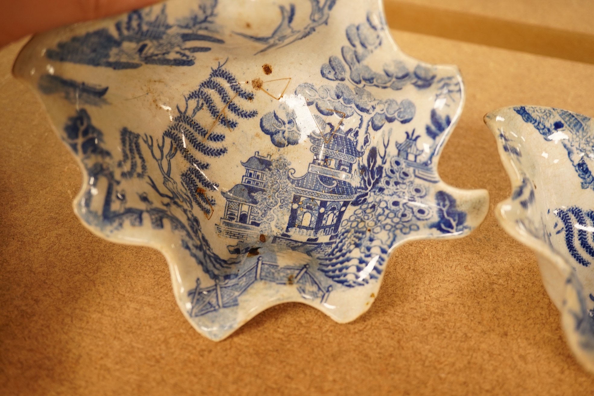 Two late 18th century Worcester or Caughley Cormorant fisherman pattern leaf pickle dishes and two early 19th century blue and white pottery leaf pickle dishes, largest 14.5cm long.